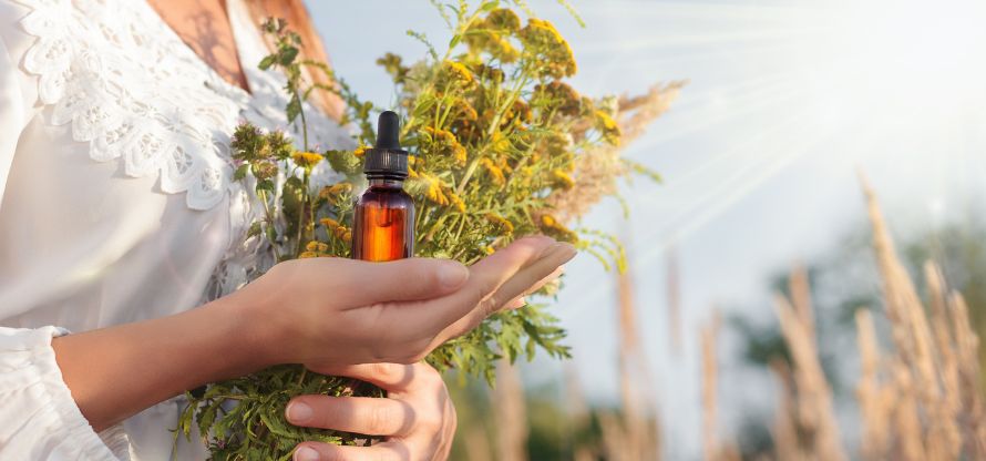 Absolventin der Bachblüten Ausbildung hält im Sonnenschein wunderbare Bachblüten in der Hand.