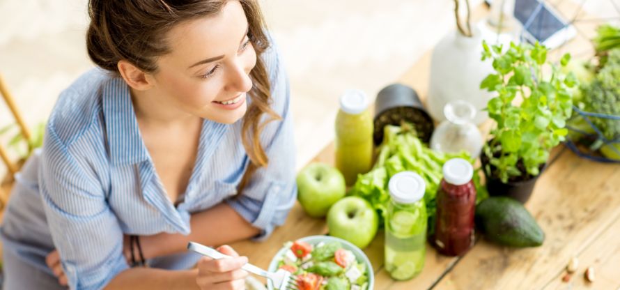 Glückliche SITYA Schülerin isst gesunden Salat bei der Ernährungsberater:in Ausbildung